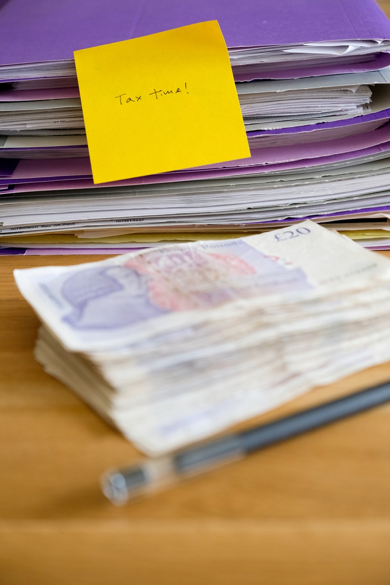 Stack of twenty pound note and tax time paperwork