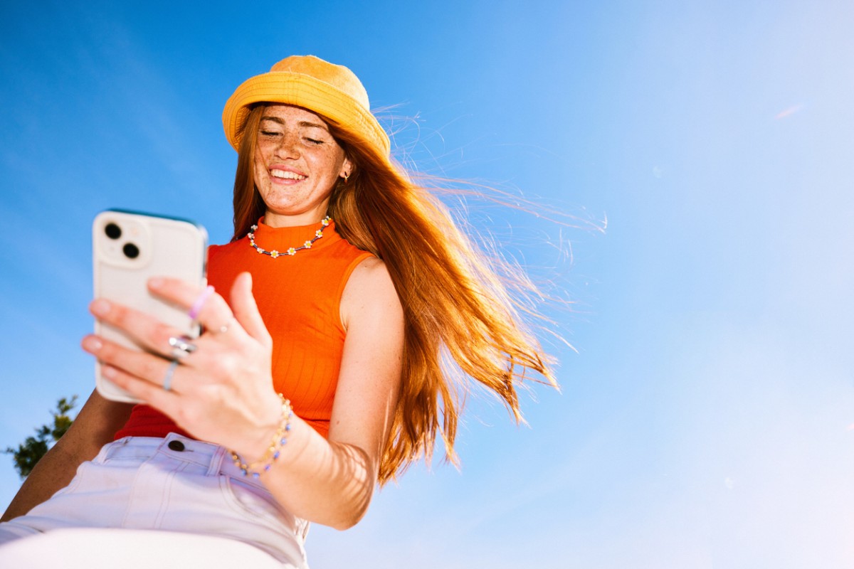 Gen Z Are Shunning Rightmove (and How you can Capitalise on it) 2 cheerful young woman with long red hair wearing sunhat checking smartphone, smiling